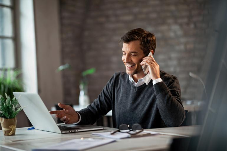 Hombre en una oficina hablando por teléfono y frente a un computador